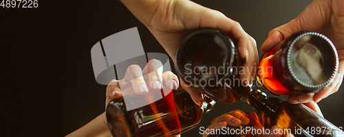 Image of Hands of young friends, colleagues during beer drinking, having fun, laughting and celebrating together. Flyer with copyspace