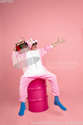 Image of Senior hipster man in stylish pink attire isolated on pink background. Tech and joyful elderly lifestyle concept