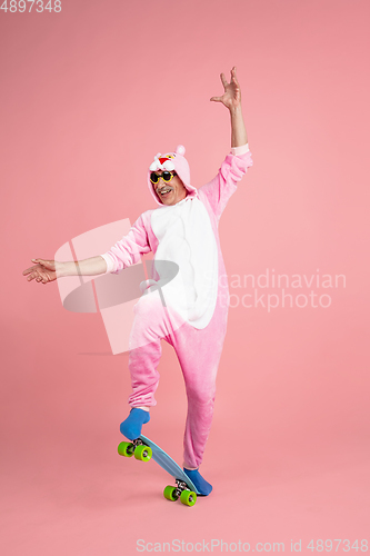 Image of Senior hipster man in stylish pink attire isolated on pink background. Tech and joyful elderly lifestyle concept