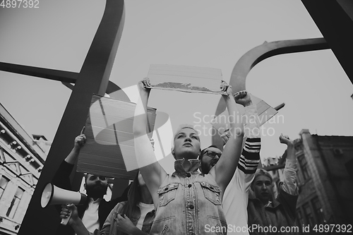 Image of Group of activists giving slogans in a rally. Men and women marching together in a protest in the city.