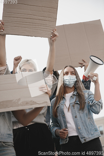 Image of Group of activists giving slogans in a rally. Men and women marching together in a protest in the city.