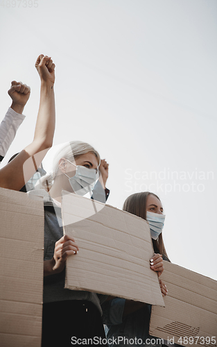 Image of Group of activists giving slogans in a rally. Men and women marching together in a protest in the city.