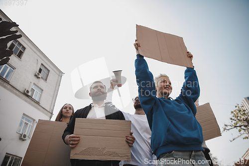 Image of Group of activists giving slogans in a rally. Men and women marching together in a protest in the city.