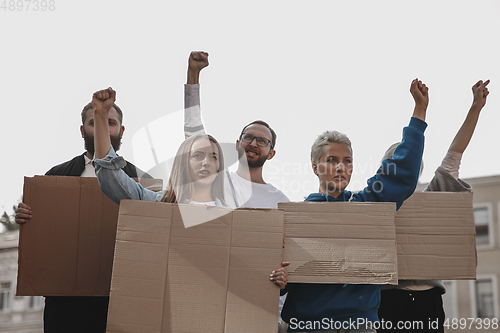 Image of Group of activists giving slogans in a rally. Men and women marching together in a protest in the city.