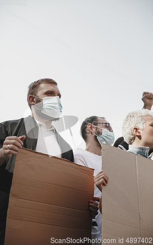 Image of Group of activists giving slogans in a rally. Men and women marching together in a protest in the city.