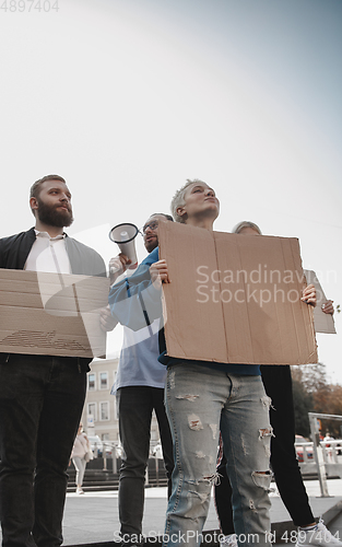 Image of Group of activists giving slogans in a rally. Men and women marching together in a protest in the city.