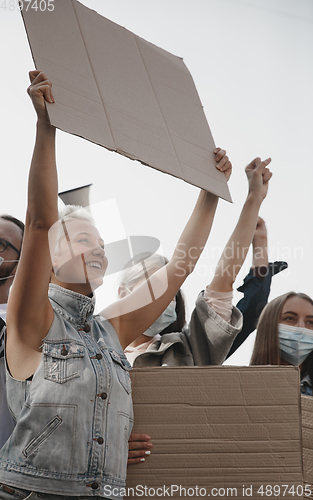 Image of Group of activists giving slogans in a rally. Men and women marching together in a protest in the city.