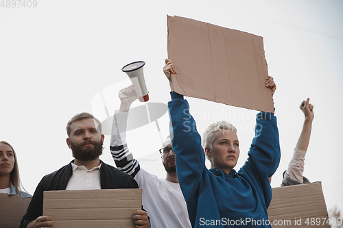 Image of Group of activists giving slogans in a rally. Men and women marching together in a protest in the city.