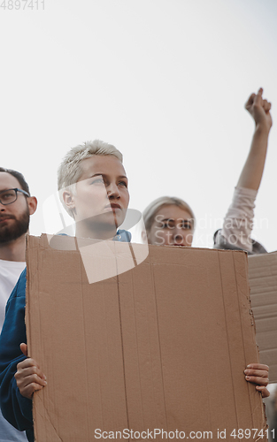 Image of Group of activists giving slogans in a rally. Men and women marching together in a protest in the city.