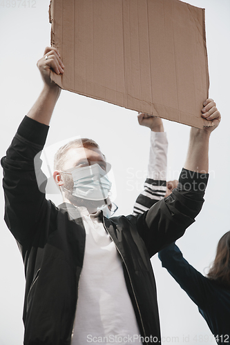 Image of Group of activists giving slogans in a rally. Men and women marching together in a protest in the city.