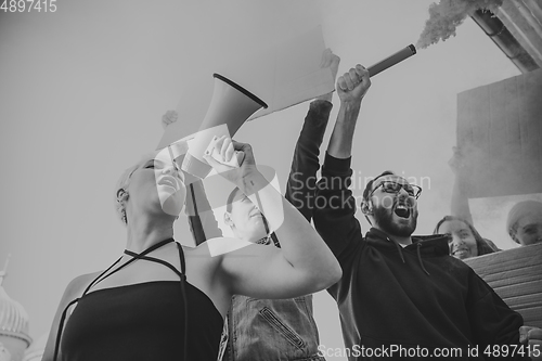 Image of Group of activists giving slogans in a rally. Men and women marching together in a protest in the city.