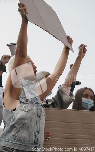 Image of Group of activists giving slogans in a rally. Men and women marching together in a protest in the city.