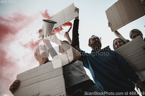 Image of Group of activists giving slogans in a rally. Men and women marching together in a protest in the city.