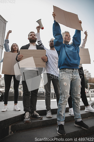 Image of Group of activists giving slogans in a rally. Men and women marching together in a protest in the city.