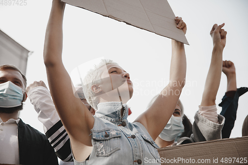 Image of Group of activists giving slogans in a rally. Men and women marching together in a protest in the city.