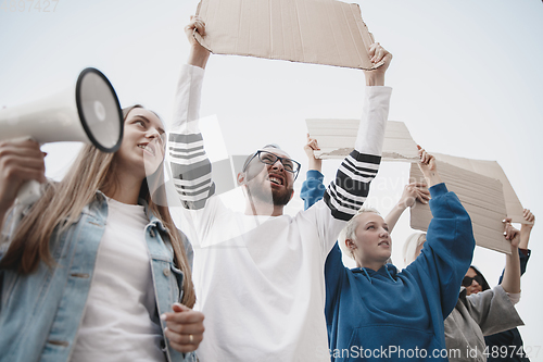 Image of Group of activists giving slogans in a rally. Men and women marching together in a protest in the city.