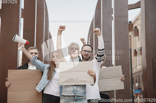 Image of Group of activists giving slogans in a rally. Men and women marching together in a protest in the city.