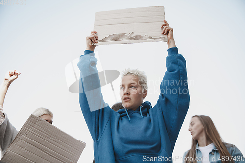 Image of Group of activists giving slogans in a rally. Men and women marching together in a protest in the city.