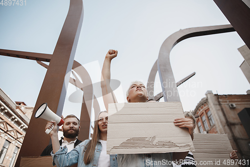 Image of Group of activists giving slogans in a rally. Men and women marching together in a protest in the city.