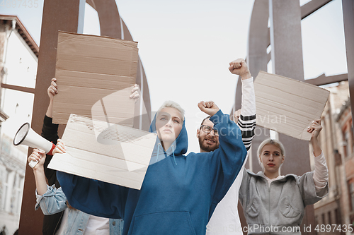 Image of Group of activists giving slogans in a rally. Men and women marching together in a protest in the city.