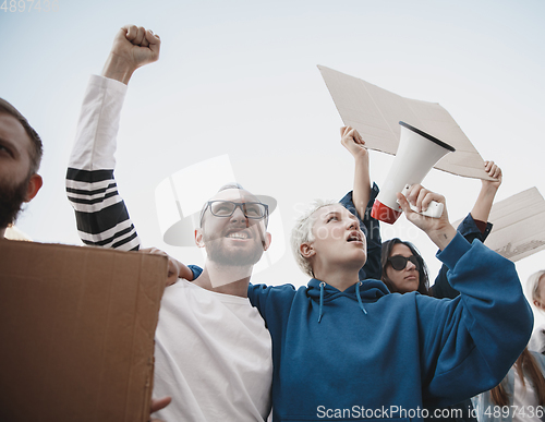 Image of Group of activists giving slogans in a rally. Men and women marching together in a protest in the city.