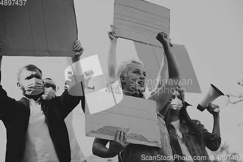 Image of Group of activists giving slogans in a rally. Men and women marching together in a protest in the city.