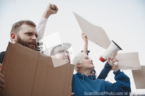 Image of Group of activists giving slogans in a rally. Men and women marching together in a protest in the city.