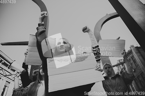 Image of Group of activists giving slogans in a rally. Men and women marching together in a protest in the city.