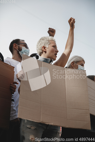 Image of Group of activists giving slogans in a rally. Men and women marching together in a protest in the city.