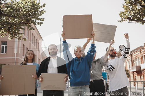 Image of Group of activists giving slogans in a rally. Men and women marching together in a protest in the city.