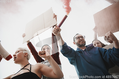 Image of Group of activists giving slogans in a rally. Men and women marching together in a protest in the city.