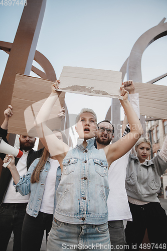 Image of Group of activists giving slogans in a rally. Men and women marching together in a protest in the city.