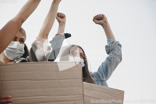 Image of Group of activists giving slogans in a rally. Men and women marching together in a protest in the city.