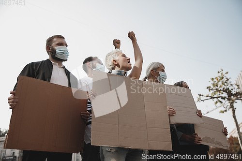 Image of Group of activists giving slogans in a rally. Men and women marching together in a protest in the city.