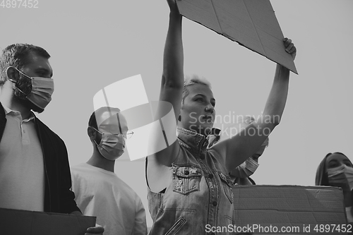 Image of Group of activists giving slogans in a rally. Men and women marching together in a protest in the city.