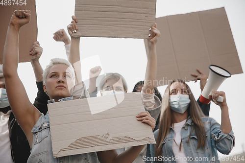 Image of Group of activists giving slogans in a rally. Men and women marching together in a protest in the city.