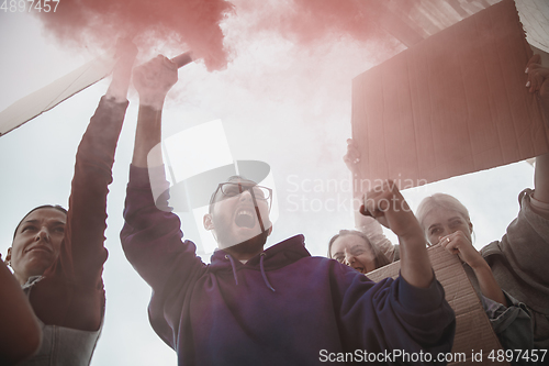 Image of Group of activists giving slogans in a rally. Men and women marching together in a protest in the city.