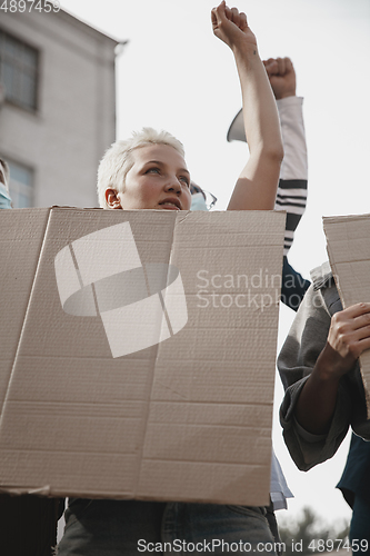 Image of Group of activists giving slogans in a rally. Men and women marching together in a protest in the city.