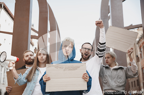 Image of Group of activists giving slogans in a rally. Men and women marching together in a protest in the city.