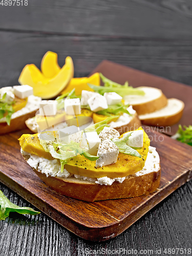 Image of Bruschetta with pumpkin and arugula on black board