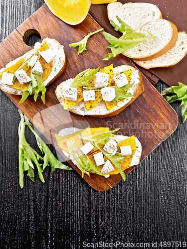 Image of Bruschetta with pumpkin and arugula on dark board top