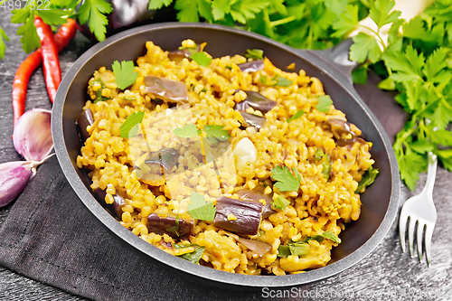 Image of Bulgur with eggplant in pan on black board