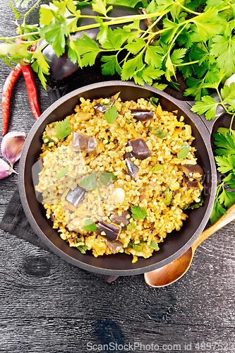 Image of Bulgur with eggplant in pan on dark board top