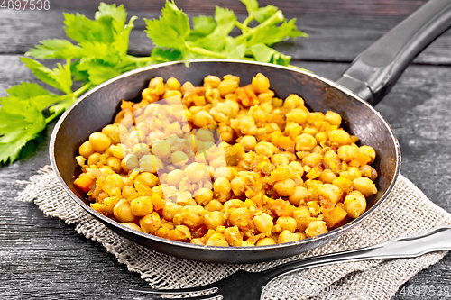 Image of Chickpeas stewed with vegetables in pan on dark board