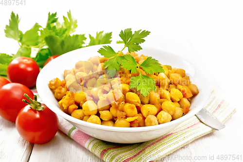 Image of Chickpeas stewed with vegetables in plate on wooden board