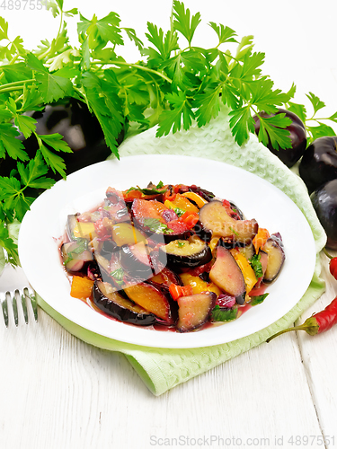 Image of Eggplant with plums in plate on white board