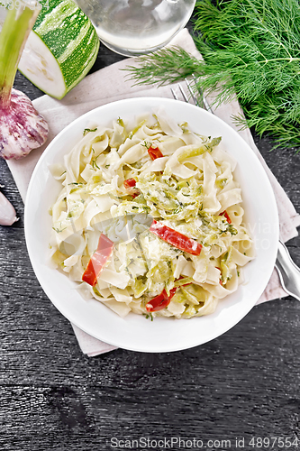 Image of Fettuccine with zucchini and hot peppers in plate on dark board 