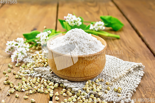 Image of Flour buckwheat green in bowl with flowers on wooden board