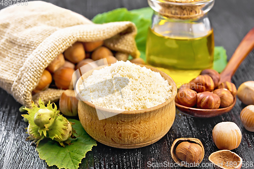 Image of Flour in bowl with nuts on dark wooden board