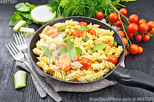 Image of Fusilli with chicken and tomatoes in pan on black board